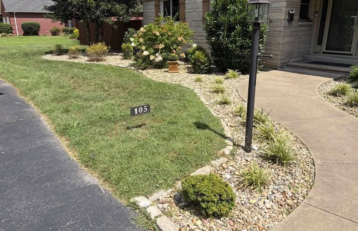 After: clean river-rock bed with grasses and a defined stone edge