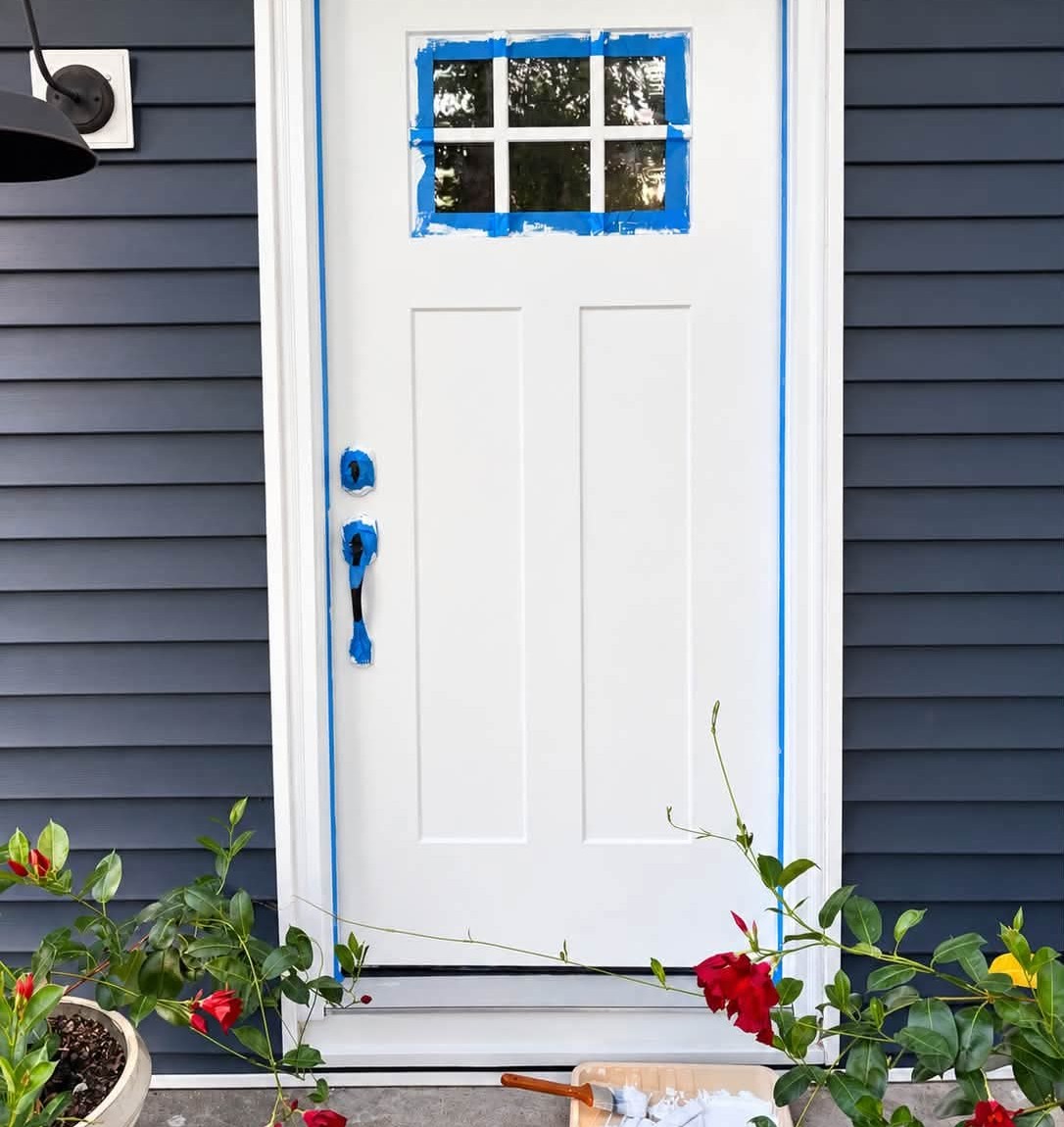 Front door freshly painted white, tape still on