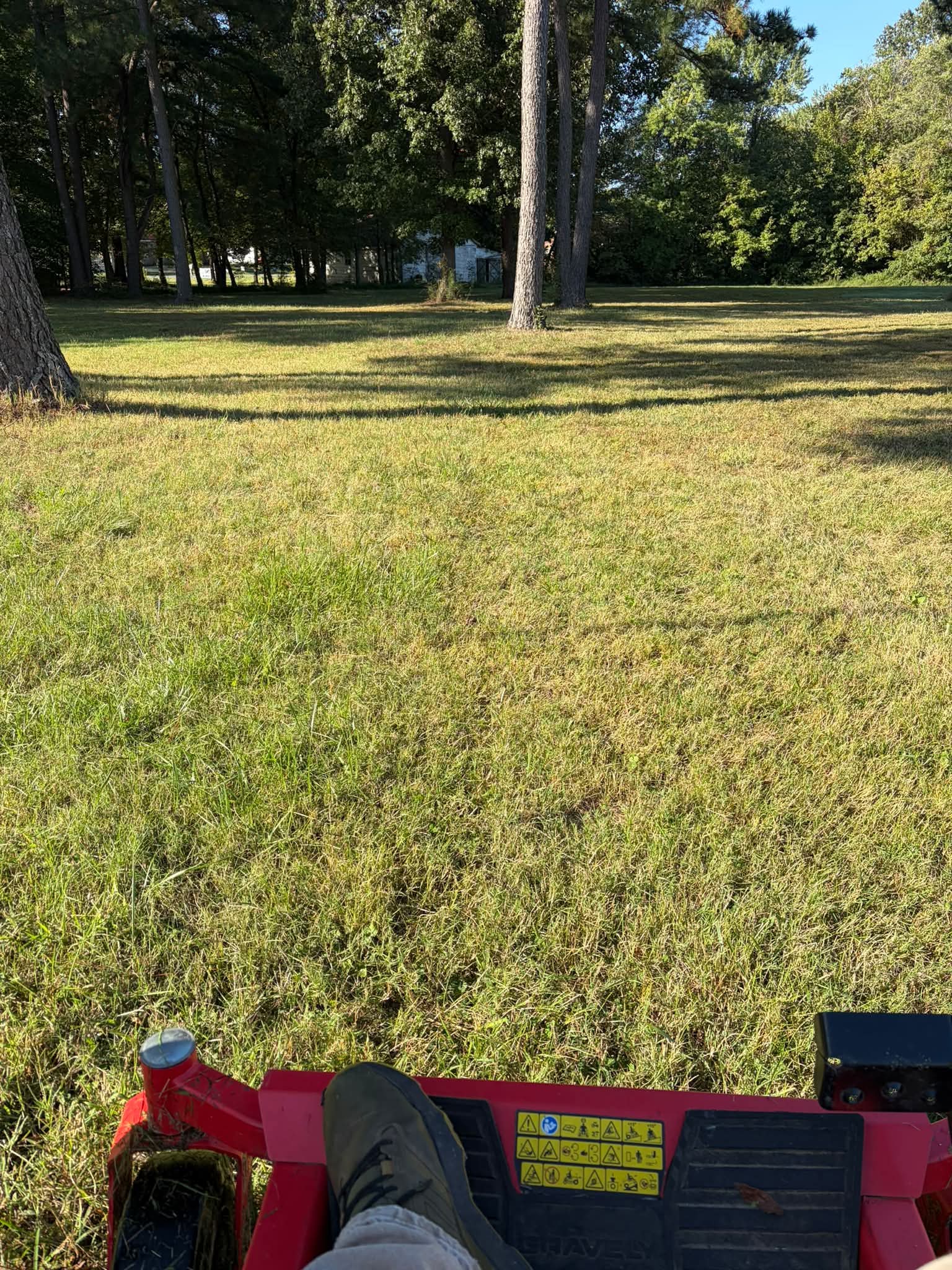 View of a freshly cut lawn from the seat of a red mower